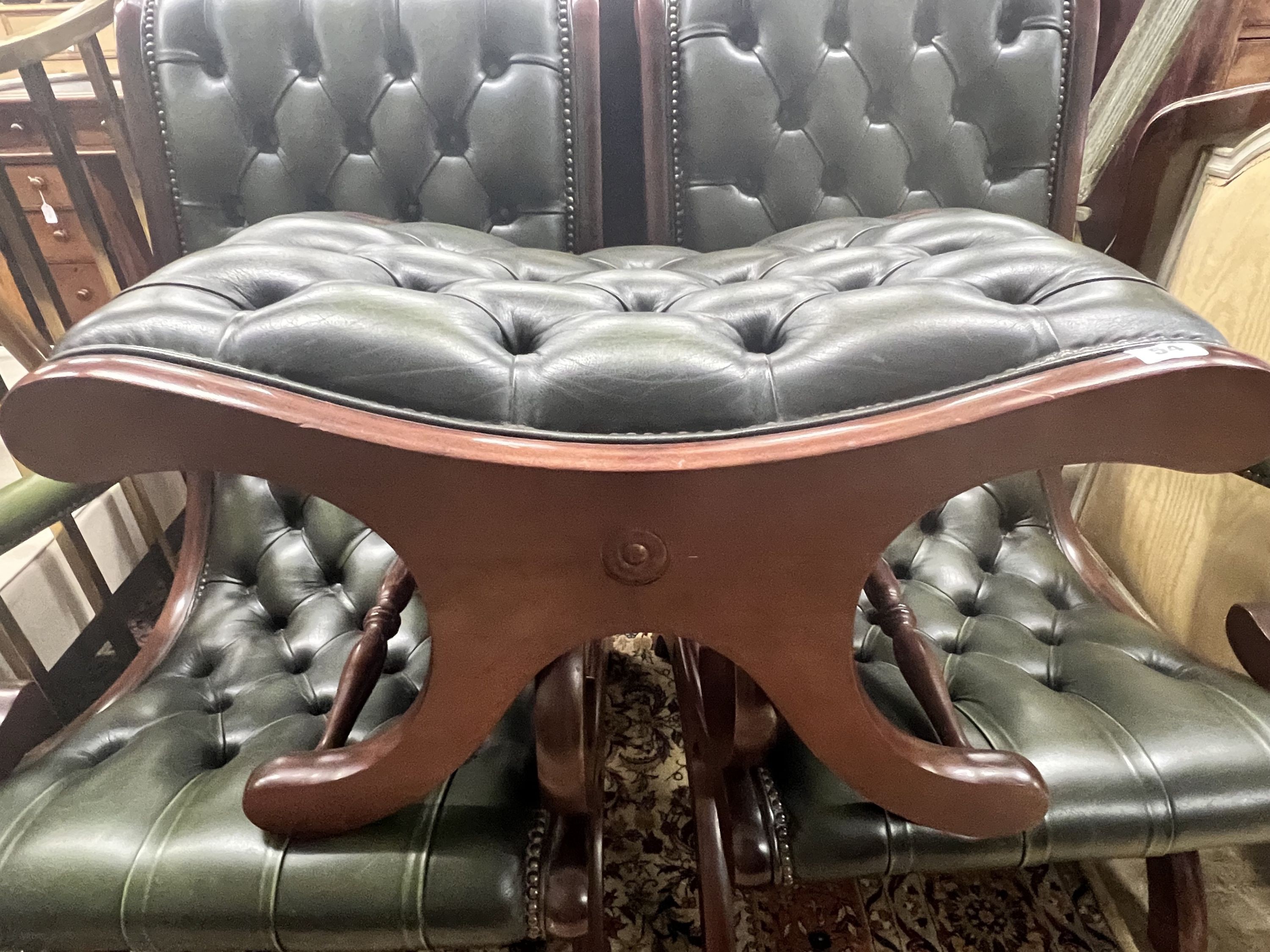 A pair of Victorian style mahogany and buttoned green leather open armchairs and matching footstool